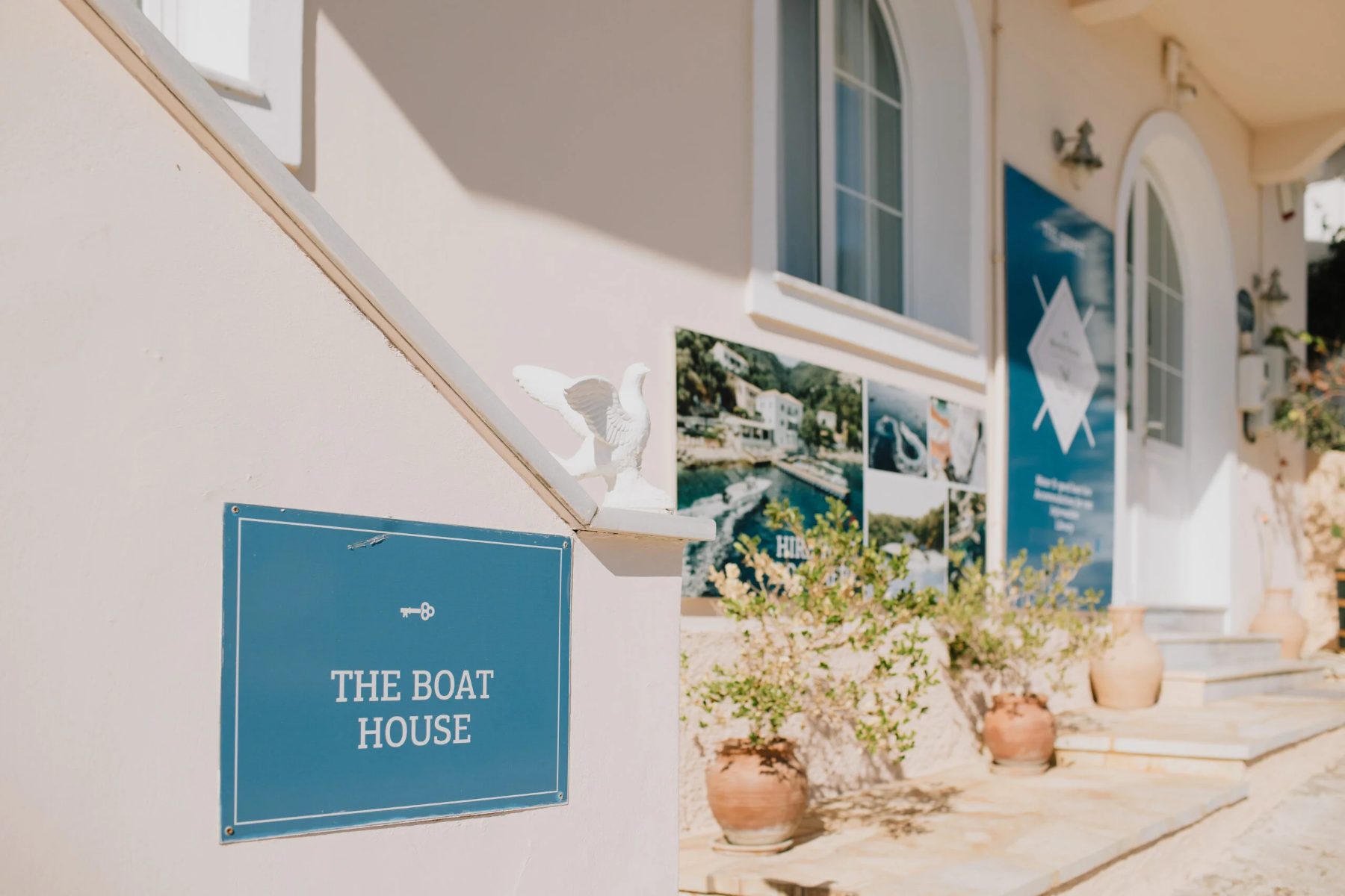Teal wayfinding sign reading The Boat House at the entrance of The White House in Kalami, Corfu, designed by Poua Design