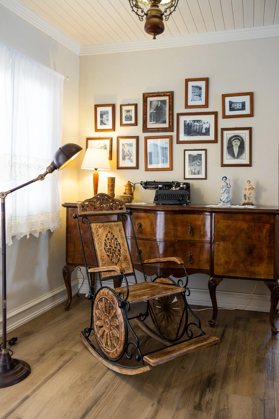 Historic interior at The White House in Kalami, Corfu, with a rocking chair, writing desk and framed family photographs